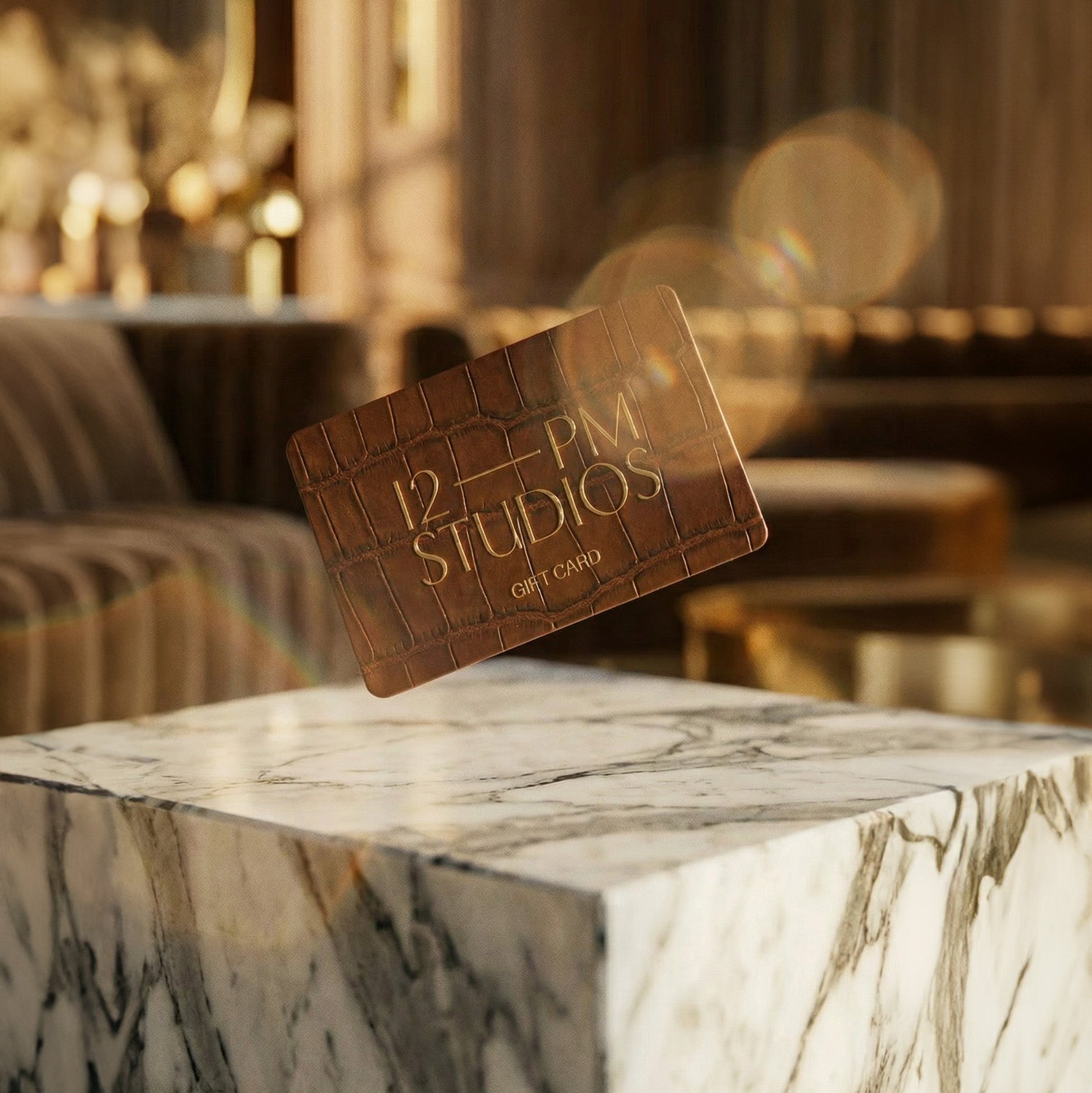 12 PM Studios business card on a marble surface with a blurred interior background