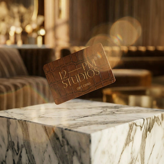 12 PM Studios business card on a marble surface with a blurred interior background